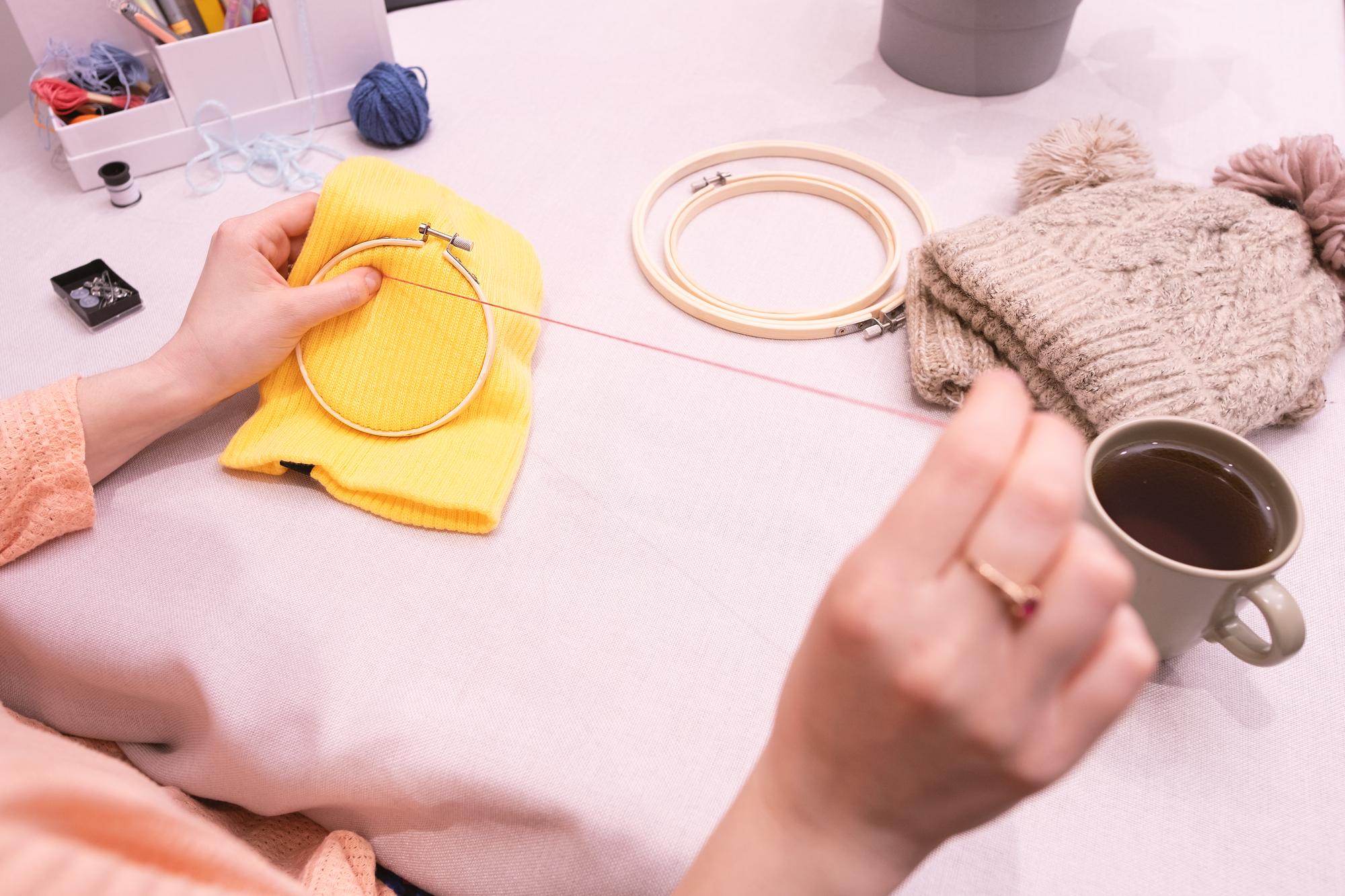 Hands preparing embroidery hoop and threads